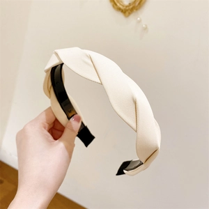 Detailed view of cream-colored twisted fabric headband with elegant texture and design