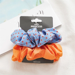 Detail of blue polka dot and solid orange fabric scrunchies on a display card