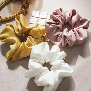 Detailed close-up of premium satin scrunchies in yellow, pink and white colors