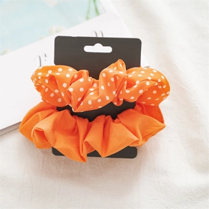 Detail of bright orange solid and polka dot hair scrunchies on display card
