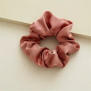 Gros plan sur un chouchou en satin rose avec texture soie et design plissé élégant