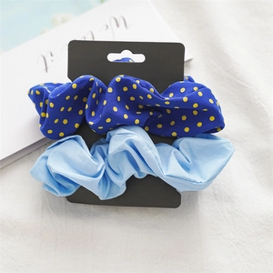 Close-up of blue polka dot and solid light blue scrunchie set on a black display card