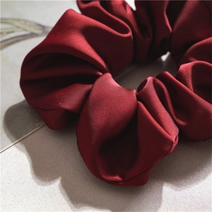 Close-up of the wine red satin fabric and soft pleated texture of this elegant scrunchie