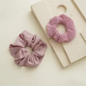 Détails des chouchous en tissu rose avec texture côtelée et reflets argentés brillants