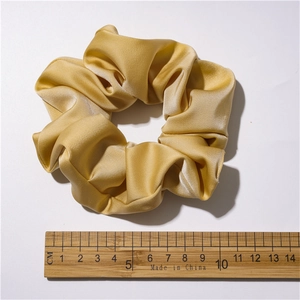 Elegant gold satin hair scrunchie with silk texture shown with ruler for size reference