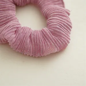 Gros plan sur un chouchou rose-violet avec texture de tissu plissé et éclat satiné