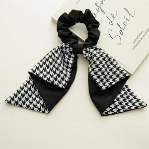 Close-up of houndstooth ribbon scrunchie with French style bow on decorative book