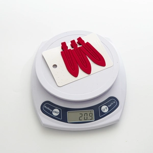 Lot de trois pinces à cheveux rouges mats pesant 20,9 grammes sur une balance digitale
