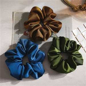 Three elegant satin scrunchies in brown blue and green colors for stylish hair styling