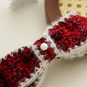 Close-up of a tweed bow hair clip featuring a white pearl and soft faux fur trim detail