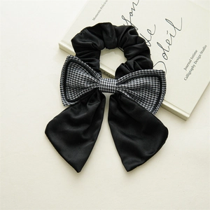 Detail of a French houndstooth bow scrunchie with elegant long ribbons on a book