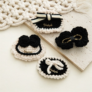 Detail of handmade crochet hair clips with pearl bow and golden handmade metal plate
