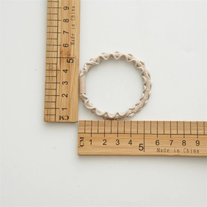 Detailed view of elastic beige wavy hair ties with a 5cm outer diameter scale