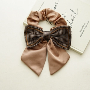 Detail of elegant champagne satin hair scrunchie with houndstooth bow and long ribbons