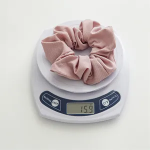 Détail d'un chouchou en tissu côtelé rose sur une balance pesant 15,9 grammes
