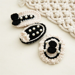 Detailed macro view of three knitted black and white hair clips with pearl bow accents