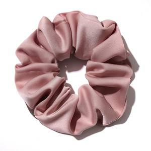 Elegant pink satin scrunchie with soft silk luster and wavy pleats on white background