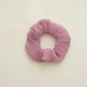 Détail d'un chouchou rose plissé en tissu scintillant avec texture en accordéon