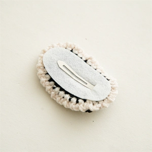 Knitted pearl bow hair clip featuring a black woolen BB clip and back structure details
