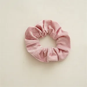Détail d'un chouchou en velours côtelé rose montrant la texture douce du tissu