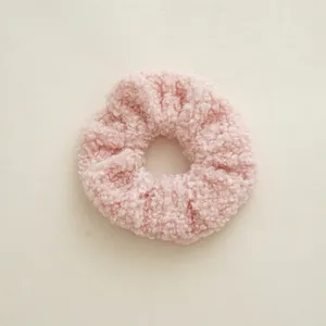 Gros plan sur le chouchou en polaire sherpa rose avec texture douce et détails bouclés