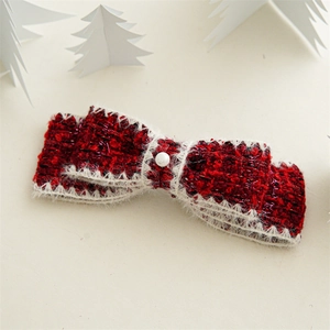 Detail of red tweed bow hair clip with faux pearl center and festive glitter details