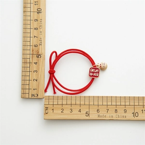 Élastique à cheveux tressé rouge festif avec pendentifs dorés et caractères porte-bonheur