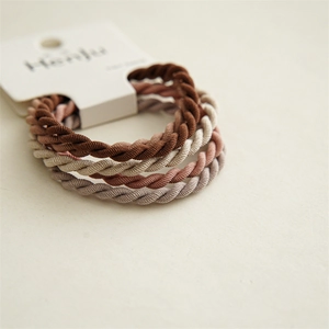 Detail of four spiral twist elastic hair ties in earth tones on white card