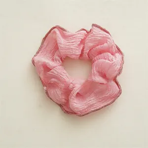 Détail d'un chouchou en tissu plissé rose avec couture foncée et texture douce