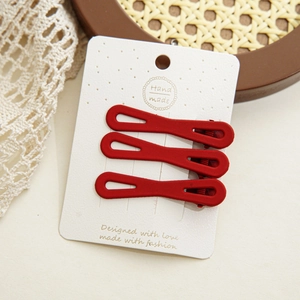 Vue détaillée de trois barrettes à cheveux rouge mat sur une carte en papier fait main