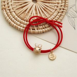 Détail d'élastique à cheveux rouge avec pendentif lapin doré et pièce de monnaie