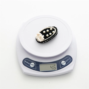 Macro shot showing 4.6g weight of black crochet hair clip with pearls and small white flower