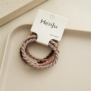 Detailed macro view of three braided elastic hair bands in soft brown and pink tones