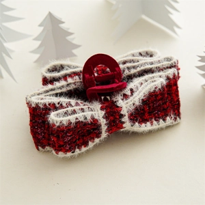 Detail of red tweed bow hair claw with faux fur trim and gold thread on a festive background
