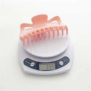 Grande pince à cheveux rose pour cheveux épais sur une balance pesant 34,4 grammes