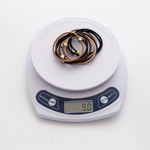 Detailed view of ten elastic hair ties with star charms on a digital scale weighing 9.0g