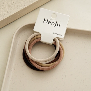Close-up of high elasticity hair bands in earth tones on a beige ceramic display tray