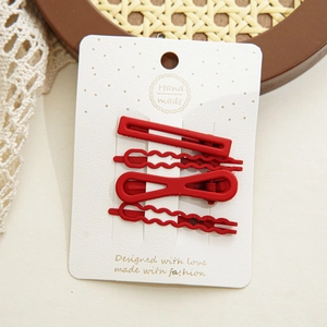 Gros plan sur un ensemble de barrettes rouges mates sur plateau vintage avec dentelle
