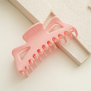 Détail d'une grande pince à cheveux rose pour cheveux épais sur un support en pierre beige