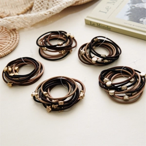Detailed view of elastic hair bands in coffee tones with matte metallic pendants