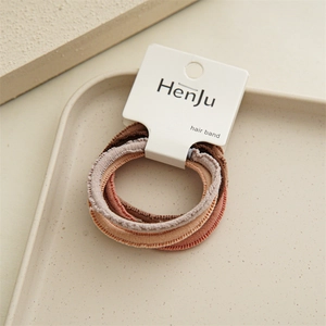 Detailed macro view of four elastic hair bands in earthy tones on a paper card display