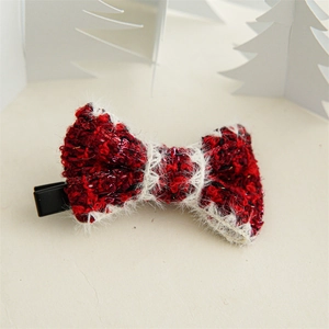 Detail of red and white knitted bow hair clip with tinsel and matte black duckbill clip