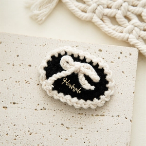 Detailed macro view of a handmade crochet hair clip with pearl and golden handmade tag