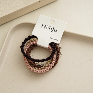 Close-up of five wavy elastic hair bands in earth tones with white card packaging