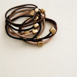 Detail of high-elasticity hair ties with matte golden square sliders in earth tones