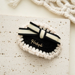 Macro shot of handmade crochet hair clip with bow and engraved metal logo plate