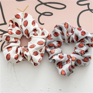 Detalle de dos gomas de pelo de terciopelo con estampado de rugby en blanco y gris
