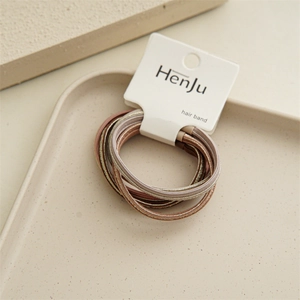 Close-up of elastic earth-tone hair bands with gold silk thread on a white paper card