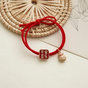 Détail d'un chouchou rouge festif avec des breloques dorées et calligraphie chinoise