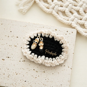 Macro view of handmade knit BB hair clips featuring ballet shoe charms and metal labels